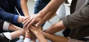 Top view hands stacked together as symbol of teambuilding.