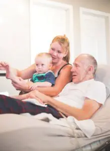 A young woman with her toddler son visiting with her elderly father who is receiving home hospice care.
