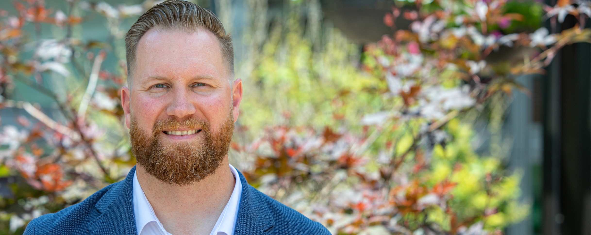 Chase Collins, director of neurosciences, stands in front of Mercy Health's Springfield Regional Medical Center hospital. He is a middle-aged white man with reddish hair and beard.