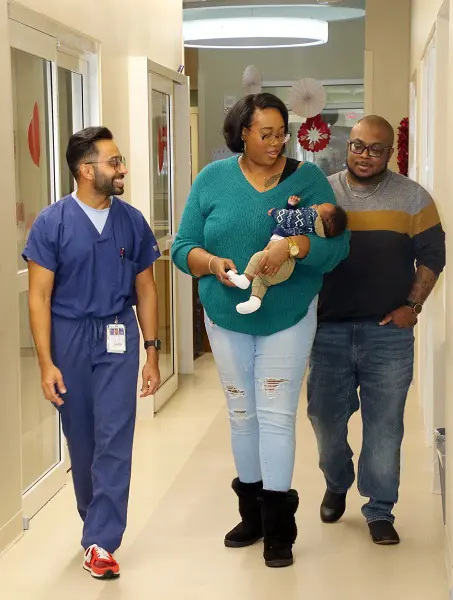 New parents walk with their newborn baby and a doctor through the Mack Pazdan Neonatal Care Unit.