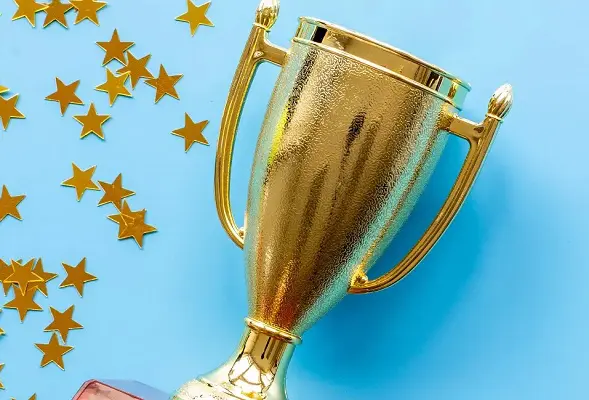A golden trophy and star confetti against a light blue background.
