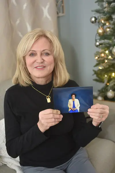 A middle-aged woman holds a photo of a deceased loved one.