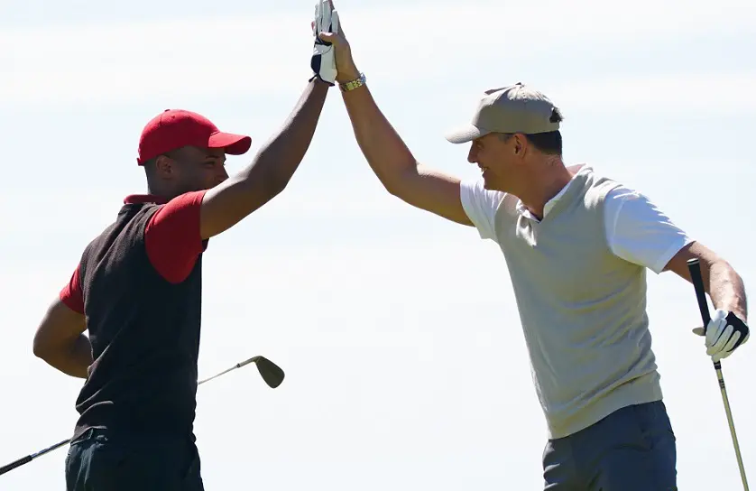 Two golfers high-five each other on a golf course.