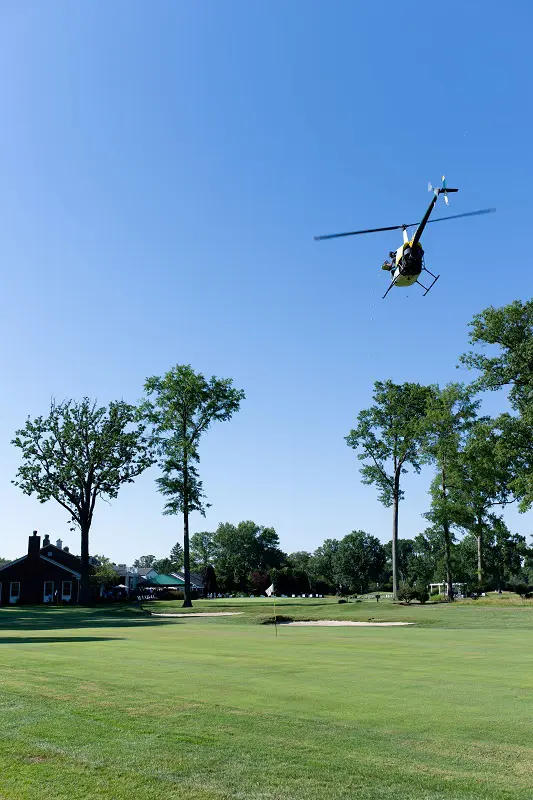 A helicopter flies over a golf course to perform a ball drop.