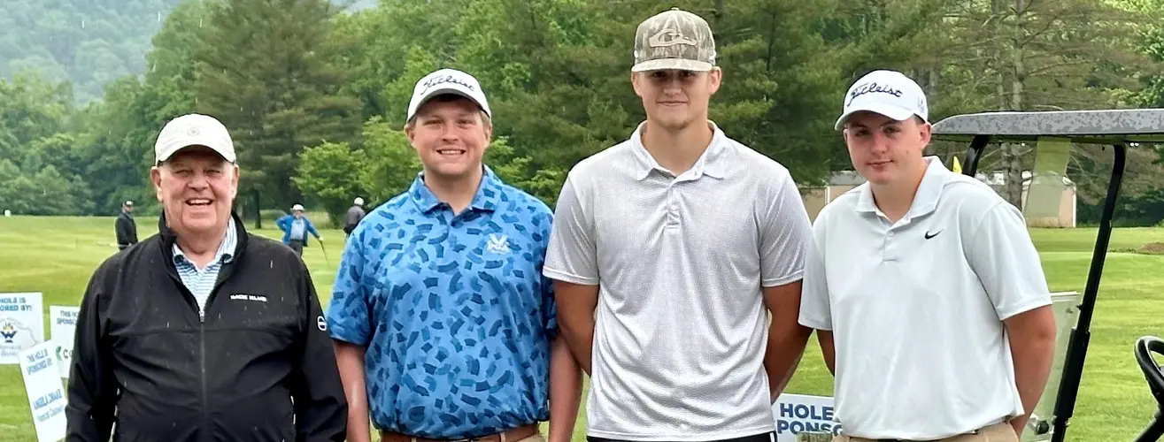 Four male golfers pose for a picture on a golf course.