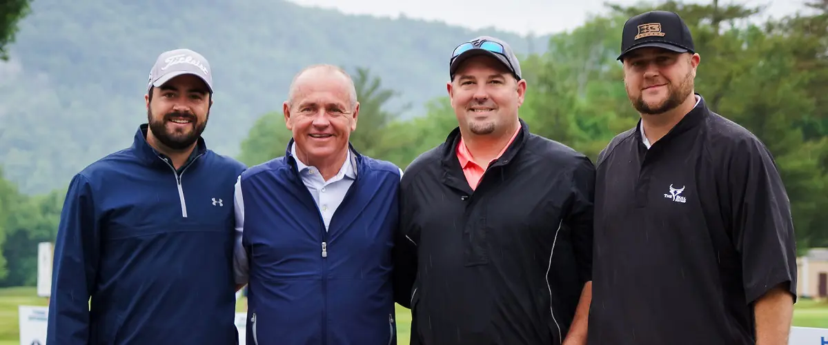 Four male golfers pose for a picture on a golf course.