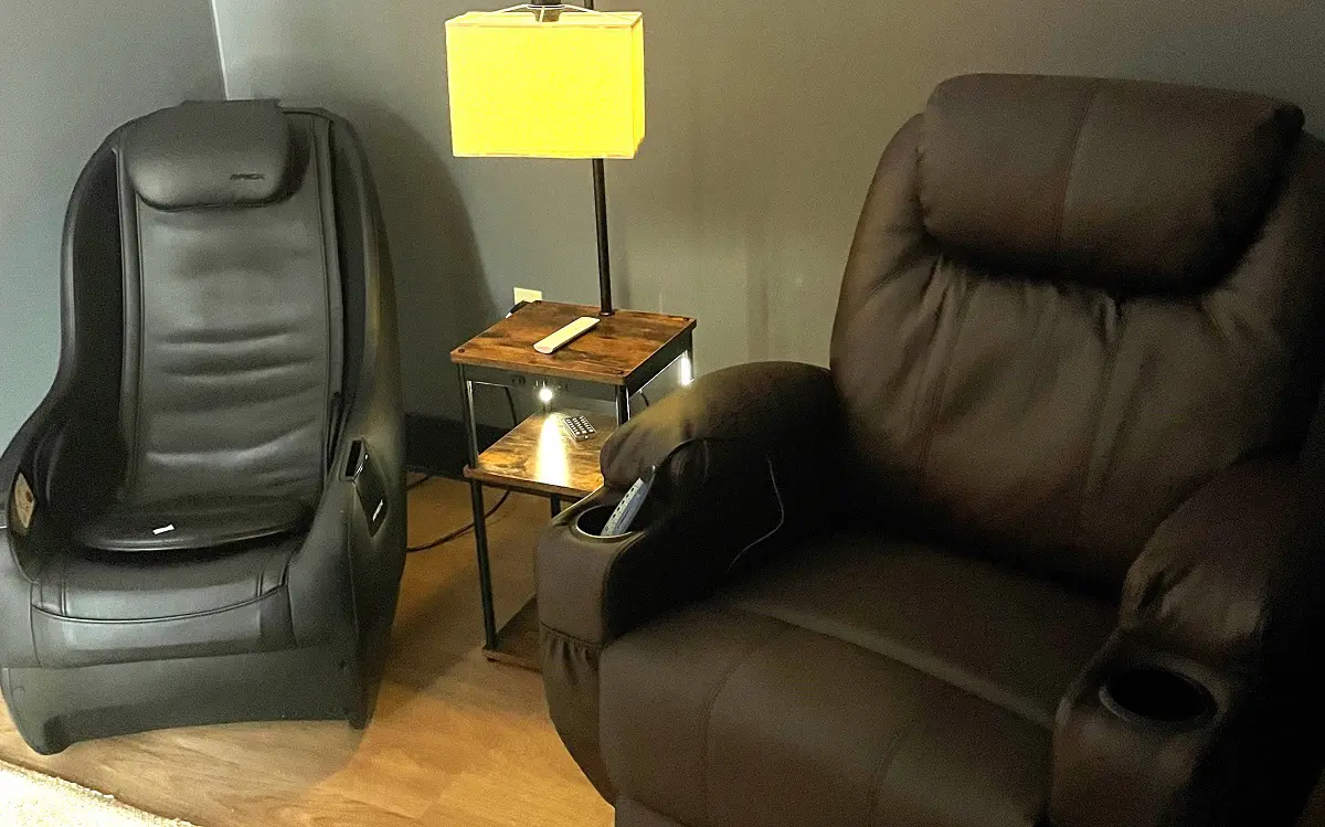 Two large, comfy recliners arranged around a small table lamp.