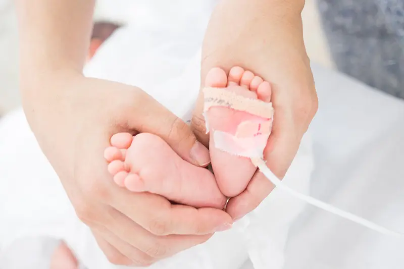 Hands wrapping a newborn baby's feet
