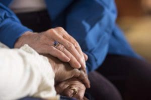 A Mercy Health volunteer offers comfort to a patient by holding her hands.