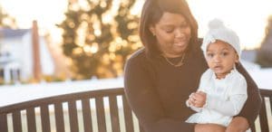 Mother and daughter sitting on bench together at park.