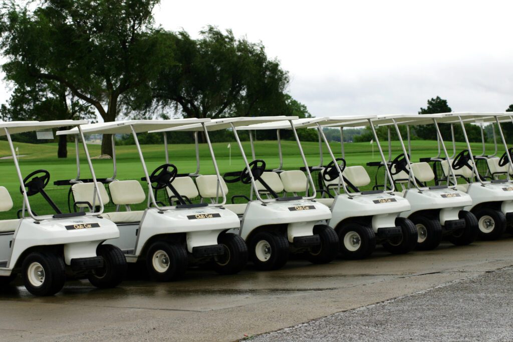 A photograph taken of golf carts parked in a row waiting for the rain to clear.