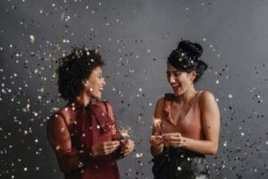 Two smiling women having a great time at a New Year's party (dark background)