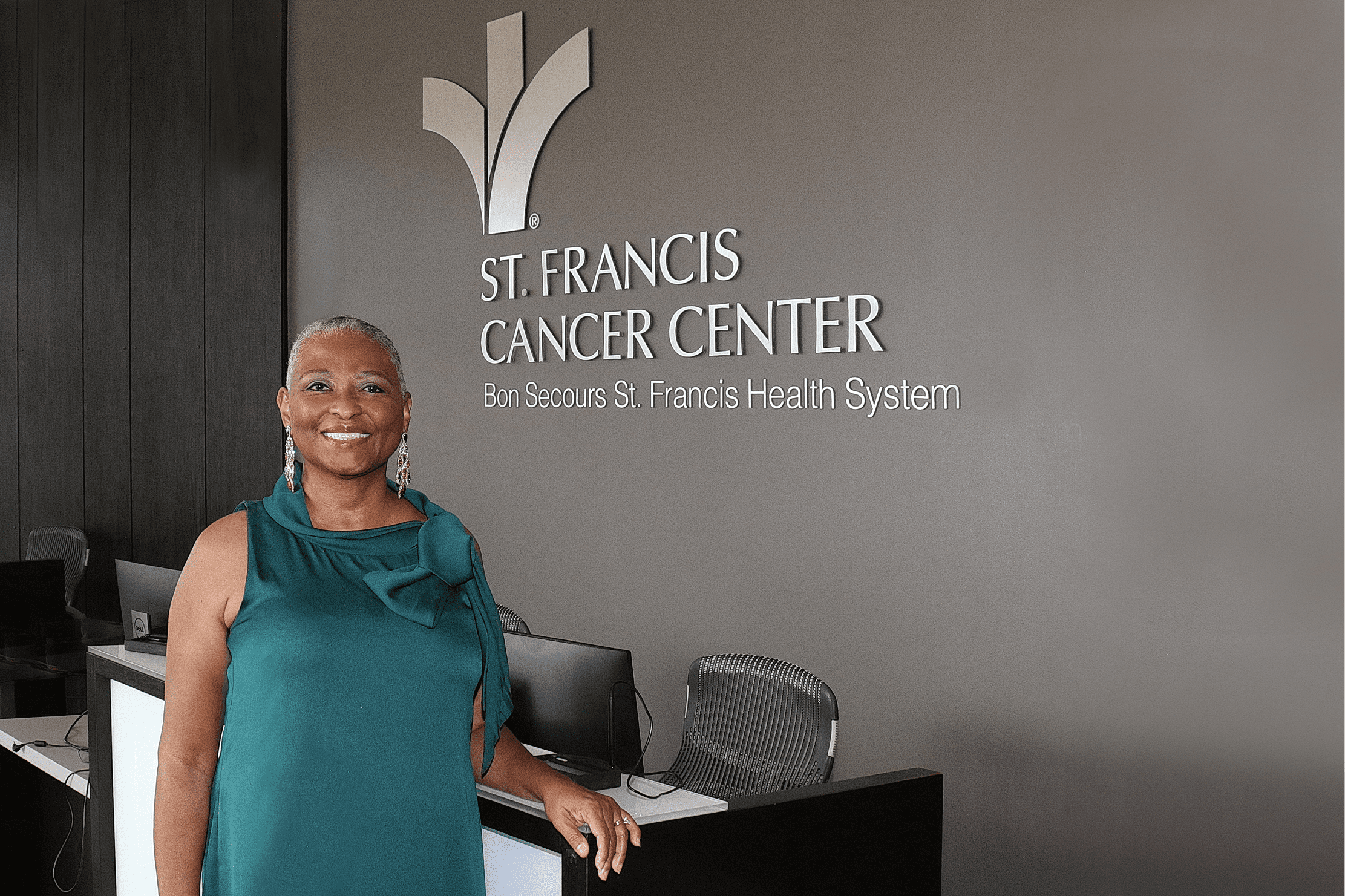 An older Black woman stands outside the St. Francis Cancer Center.