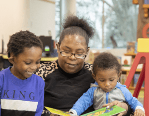 A mother reads to her two young children in a library.