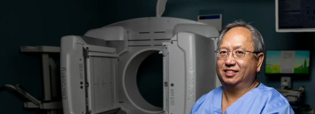 A male nurse stands in front of an MRI machine.