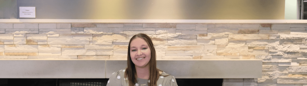 A teenage girl smiles in front of the NICU at St. Rita's Medical Center.