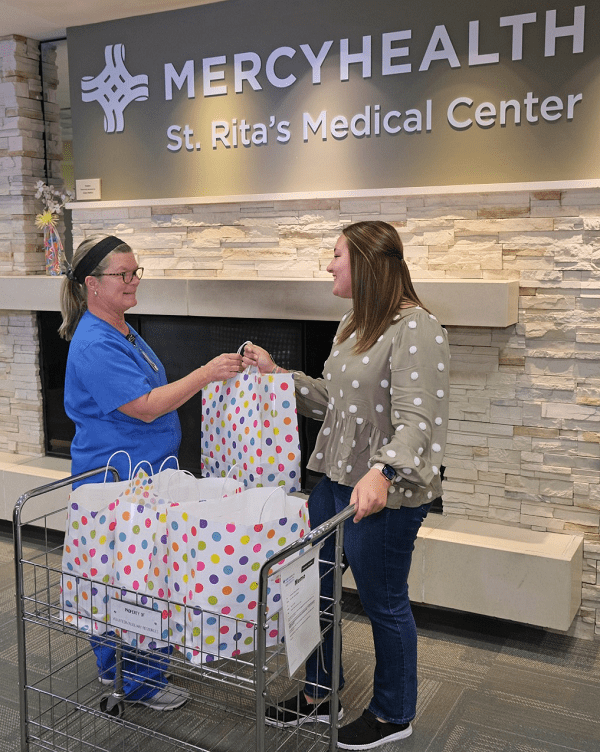 A teenage girl hands gift bags over to a NICU nurse at St. Rita's.