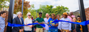 A crowd of people gathers to cut a big, blue ribbon at the opening of Unity Park in Franklin Square, MD.