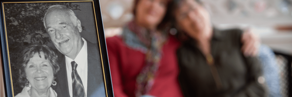 A black and white photo of Retta and Chuck Folsom, who was cared for by Mercy Health Hospice Lourdes, is in the foreground. In the background, Retta is embraced by her daughter, Julie.