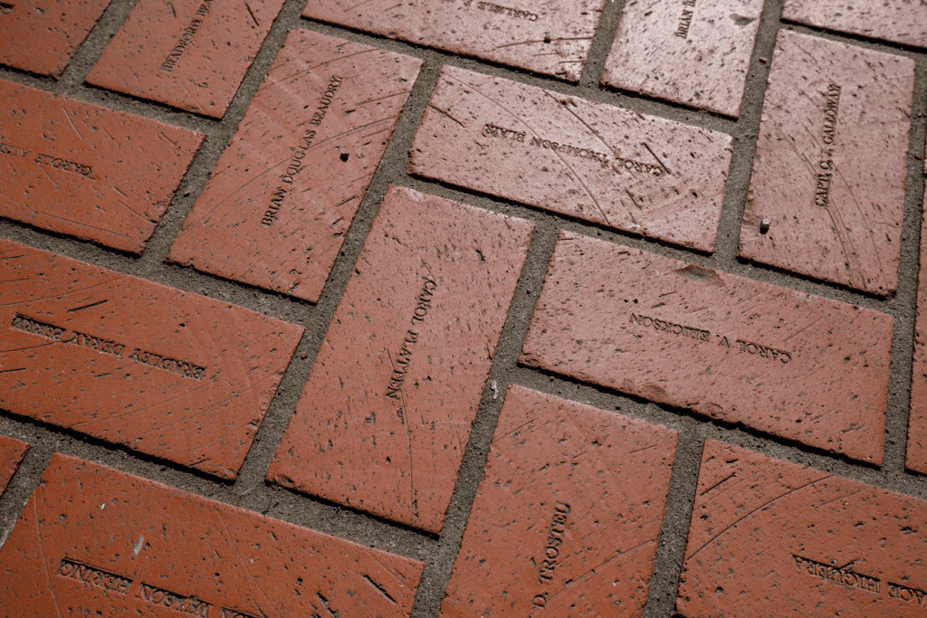 Red bricks engraved with names are laid in a pattern.