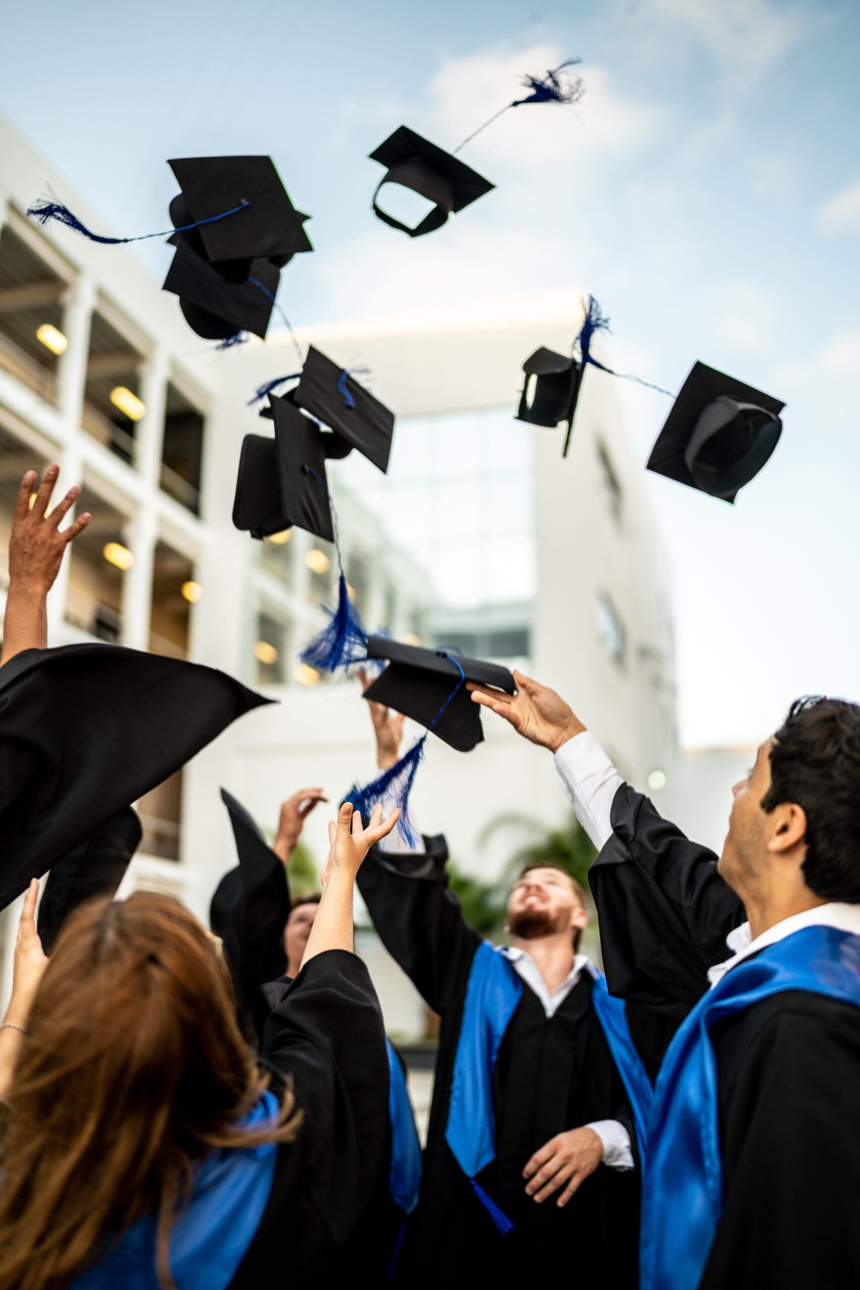 Young graduates throwing their mortarboard in the air while celebrating ...