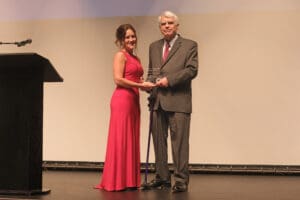 A man and woman pose together on stage at a gala