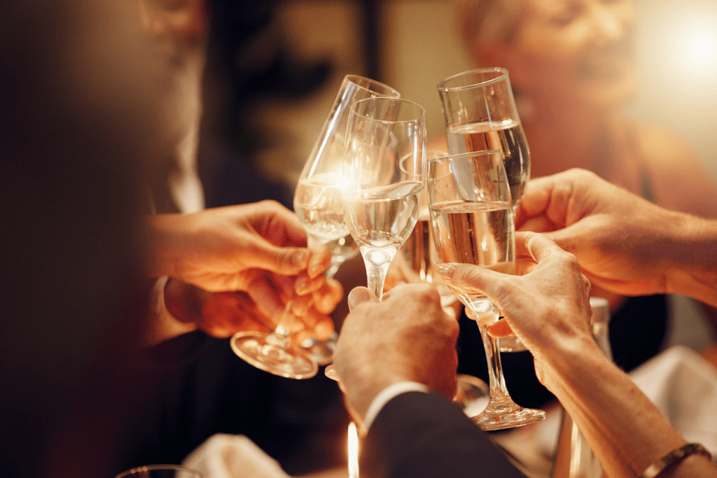 People cheers with champagne drinks or wine glasses at dinner gala.