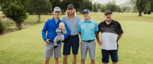 A group of golfers pose for a picture at the golf course.
