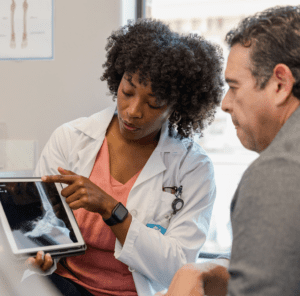 Female orthopedic surgeon points to foot x-ray on digital tablet.