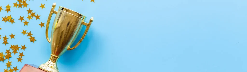 A golden trophy and star confetti against a light blue background.