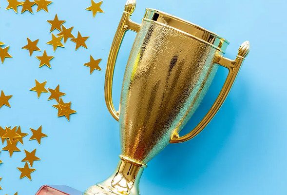 A golden trophy and star confetti against a light blue background.