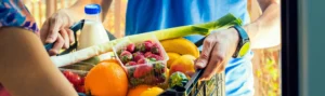 A worker delivers fresh, healthy groceries to someone in their home.