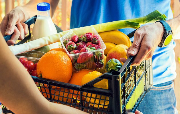 A worker delivers fresh, healthy groceries to someone in their home.