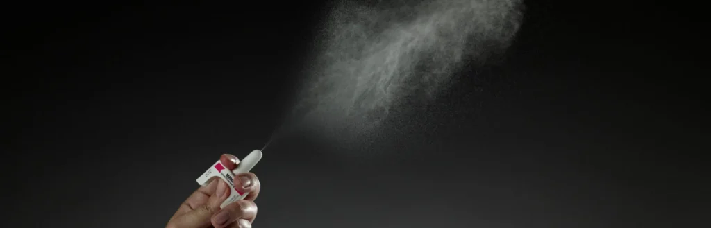 A hand spraying a dose of naloxone nasal spray.
