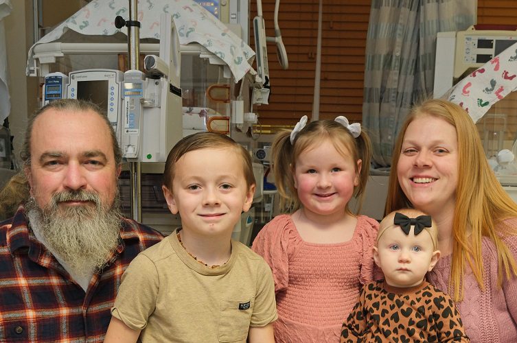 A young family together in a NICU medical setting.