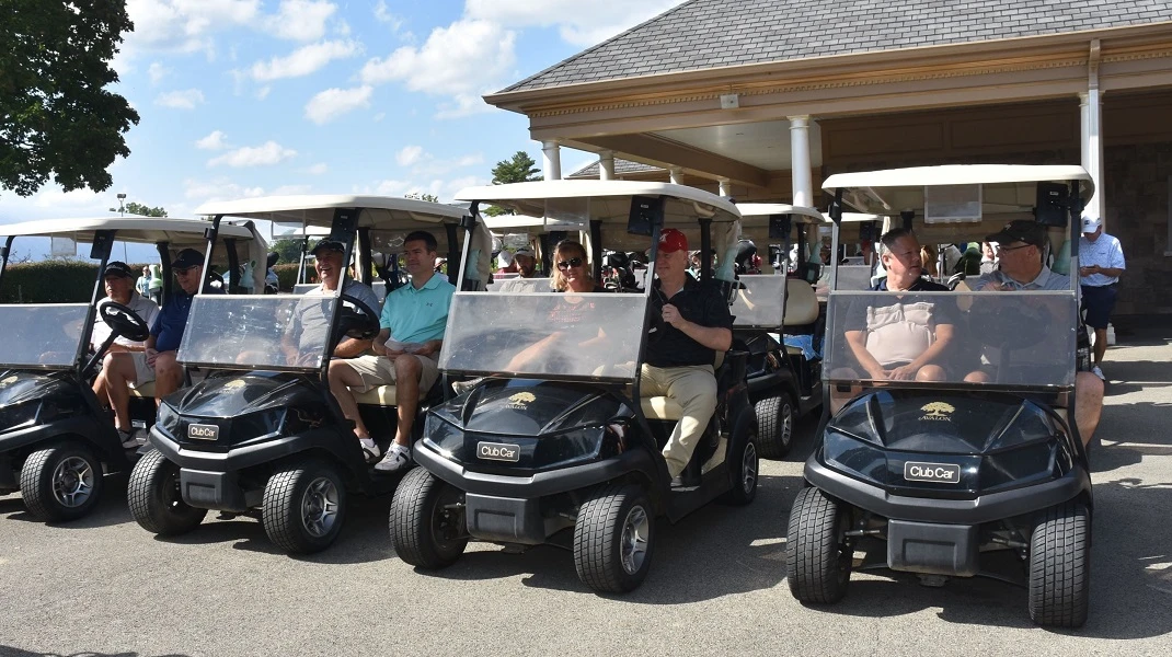 Golfers aboard their golf carts in a row.