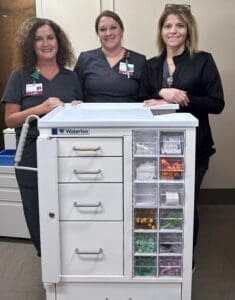 Three lab staff members at Mercy Health - Marcum and Wallace Hospital pose with a new phlebotomy cart.