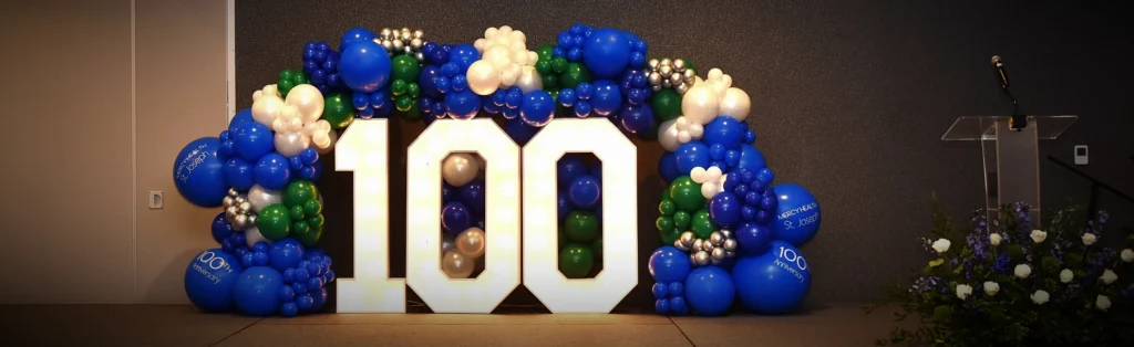 An indoor balloon wreath and light display that says 100.