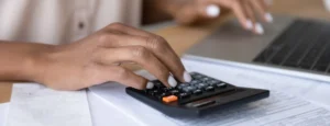 Close-up of a woman's manicured fingers tapping on a calculator.