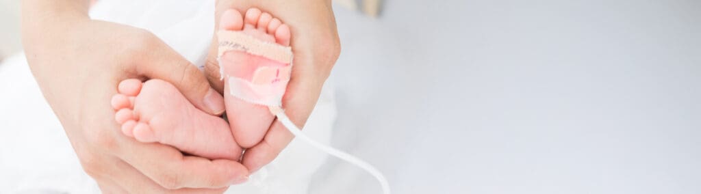Hands wrapping a newborn baby's feet