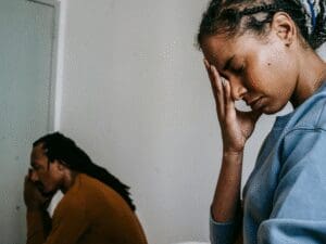 A man and woman cover their faces with their hands