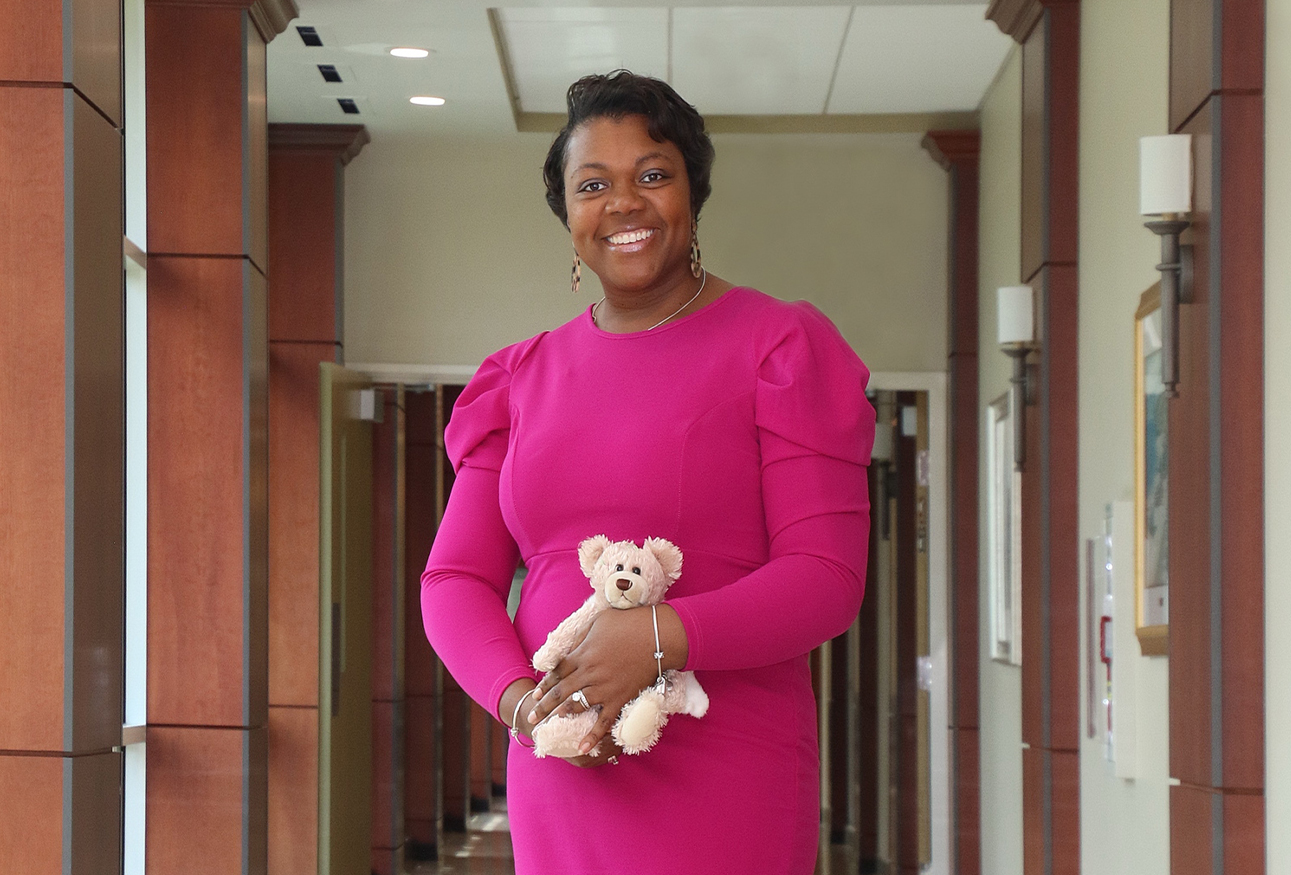 A woman smiles while holding a teddy bear