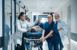 Medical team rushing a patient on a wheeled stretcher through a hospital hallway, with a doctor administering IV fluids