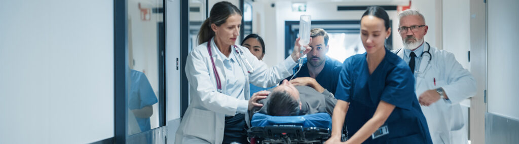 Medical team urgently transports a patient on a stretcher through a hospital corridor. The mood is tense and focused as they attend to the patient's needs.