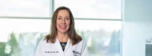 Portrait of Dr. Anne Marie Tuohy, pediatrician, smiling in a bright clinic with Bon Secours Pediatrics logo on her coat.