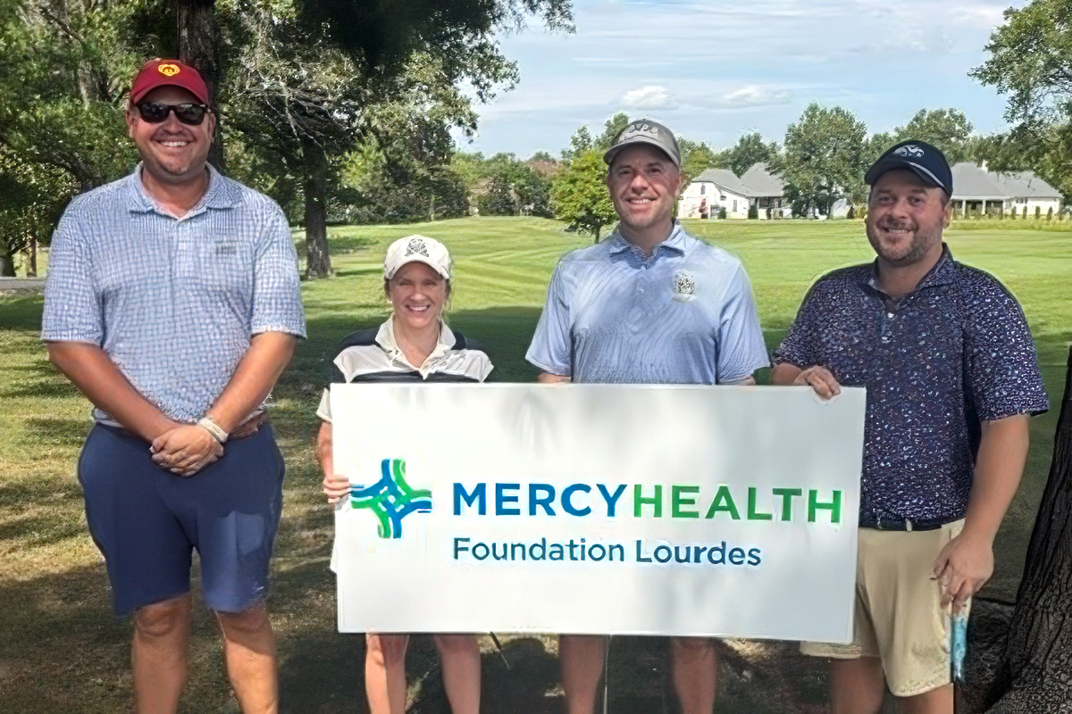 The winning team for the Charity Golf Open four team members holding a Mercy Health Sign with the golf course in the background
