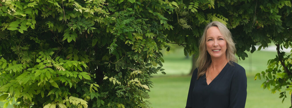 landscape portrait of Victoria Kimmel outside next to a green garden arch