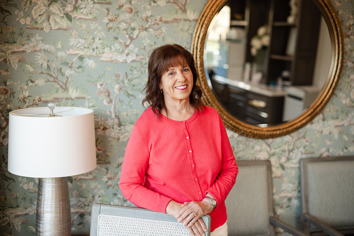 Headshot of Connie Hutson in a wallpapered room with a mirror in the background