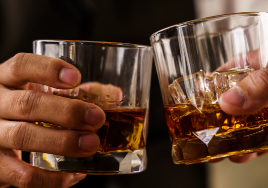 Two men cheers rocks glasses of bourbon.