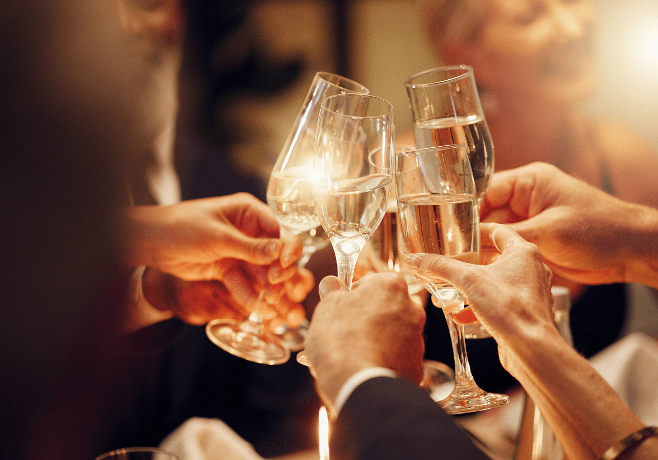 People cheers with champagne drinks or wine glasses at dinner gala.